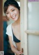 A smiling young woman leaning against a door.