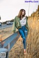 A woman leaning against a fence in a field.