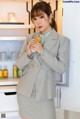 a woman standing in front of a refrigerator holding a cup