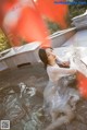 A woman in a white dress sitting in a pool of water.