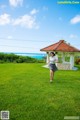 A woman running across a lush green field.