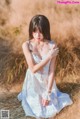 A woman in a white dress sitting in a field.