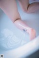 A person with a tattoo on their foot in a bathtub.