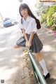 A young woman in a school uniform leaning on a railing.