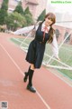 A woman in a school uniform standing on a track.