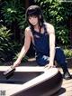 A woman sitting on top of a wooden deck next to a pool.