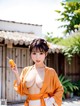 A woman in an orange kimono holding a carrot.